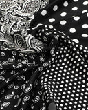 Close-up of a black and white paisley print silk scarf featuring white polka dots, showcasing intricate fabric details.