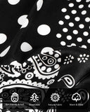 Close-up of a black and white paisley print silk scarf featuring intricate designs and white dots, showcasing elegance and style.