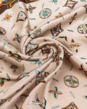 A close-up of a beige silk scarf featuring a vibrant feather alphabet pattern in various colors.
