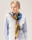 A woman models a blue shirt paired with a silk scarf featuring an abstract design, showcasing elegance and style.
