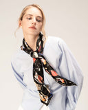A woman models a blue shirt paired with a luxurious black silk scarf, showcasing elegance and style.