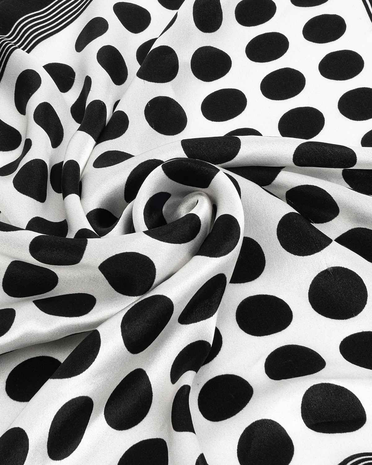 A chic black and white polka dot silk scarf, beautifully displayed, highlighting its sophisticated pattern and smooth fabric.