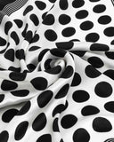 A chic black and white polka dot silk scarf, beautifully displayed, highlighting its sophisticated pattern and smooth fabric.