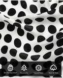 A close-up of a silk scarf with black and white polka dots and various symbols highlighting the characteristics and details of its material.
