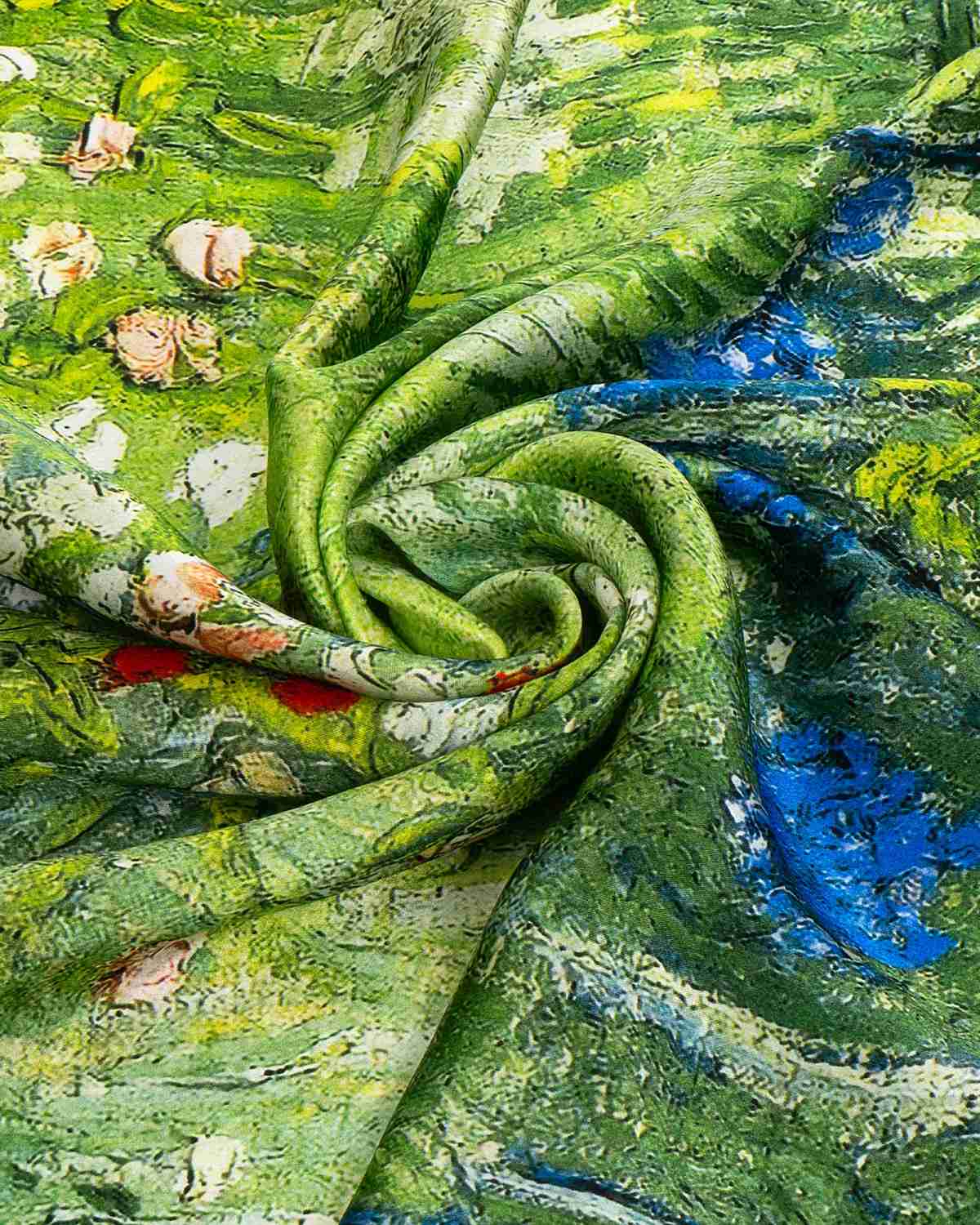 Close-up of a silk scarf featuring a vibrant green fabric adorned with intricate flowers and leaves.
