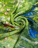 Close-up of a silk scarf featuring a vibrant green fabric adorned with intricate flowers and leaves.