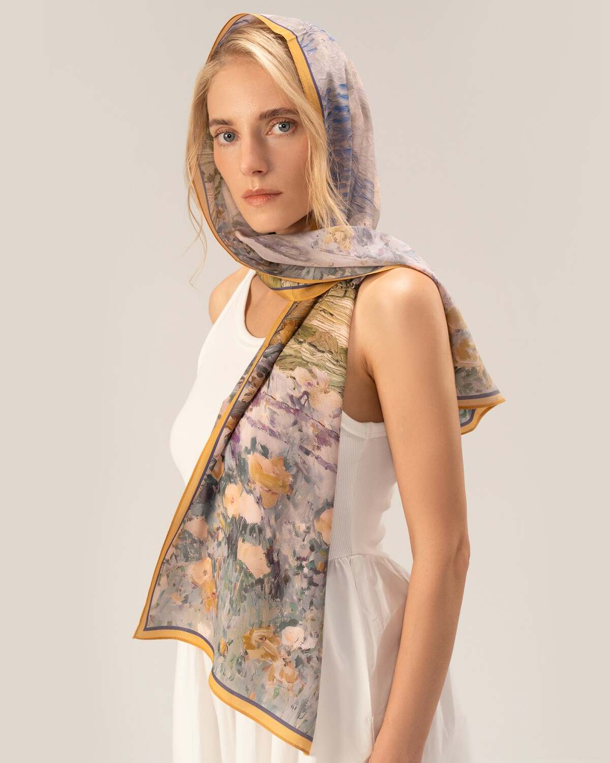 A woman showcases a floral print silk head scarf, adding a touch of elegance to her attire with its rectangular design.