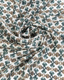 Close-up of a silk scarf featuring a green and brown geometric pattern, showcasing intricate design details.