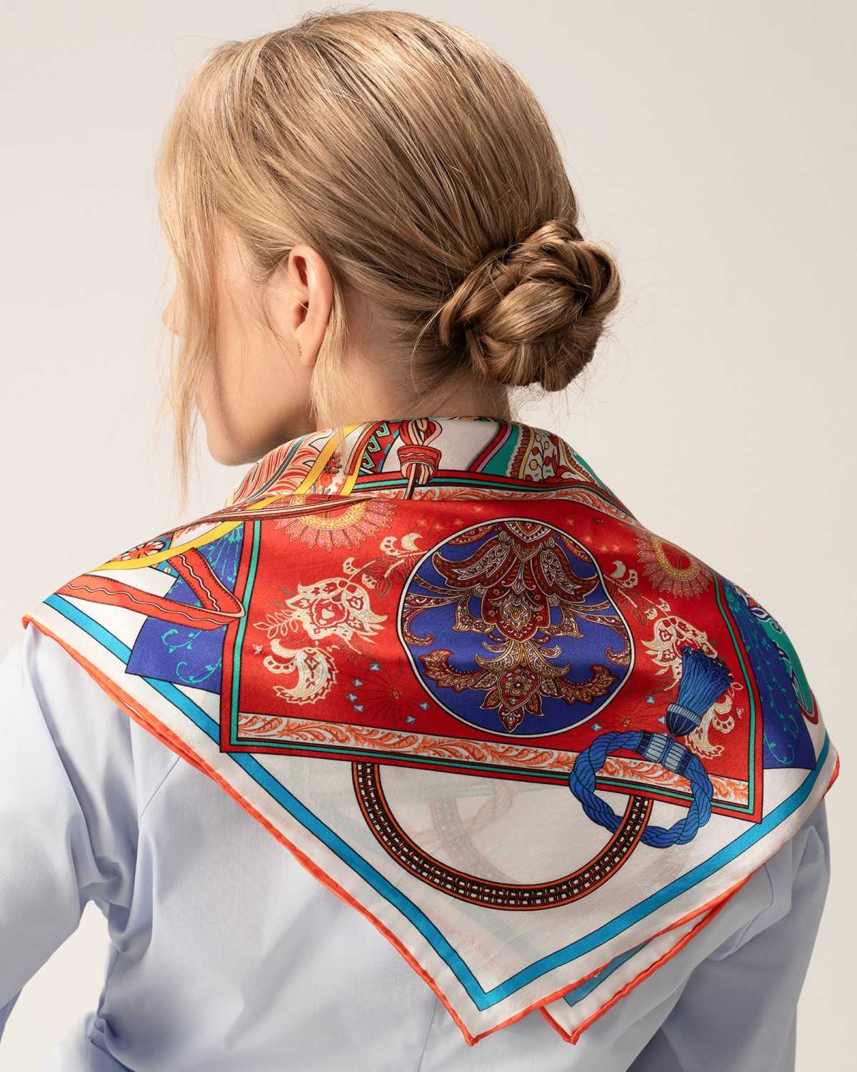 A model showcases a silk scarf in red and white, elegantly draped over her shoulder.