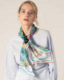 A model showcases a blue shirt paired with a vibrant, patterned silk scarf, highlighting a stylish ensemble.