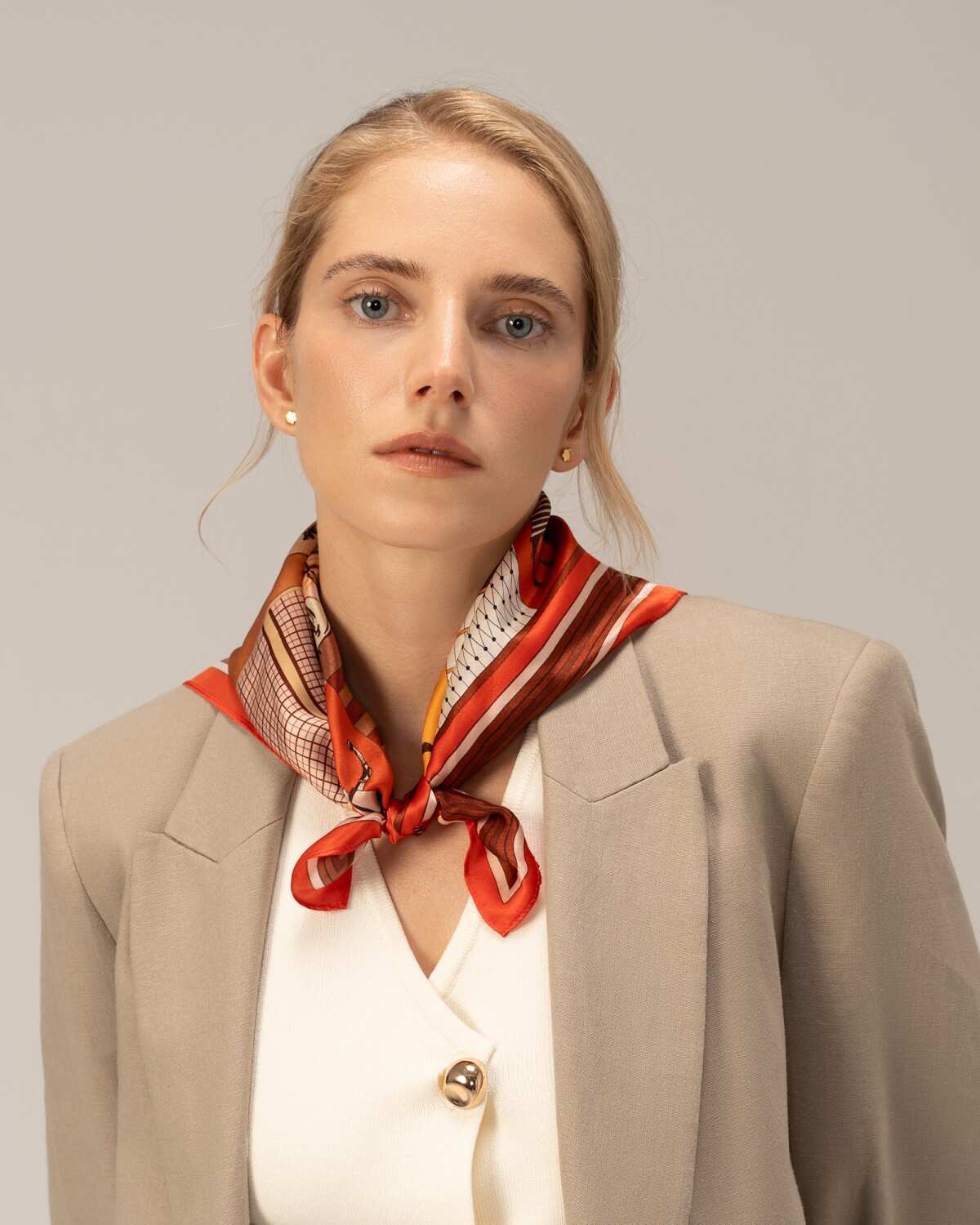 A model wearing a silk red scarf and a stylish blazer, showcasing elegance and sophistication.