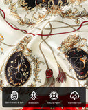 Close-up of a red and white silk scarf featuring intricate gold and black designs, showcasing its elegant texture and patterns.