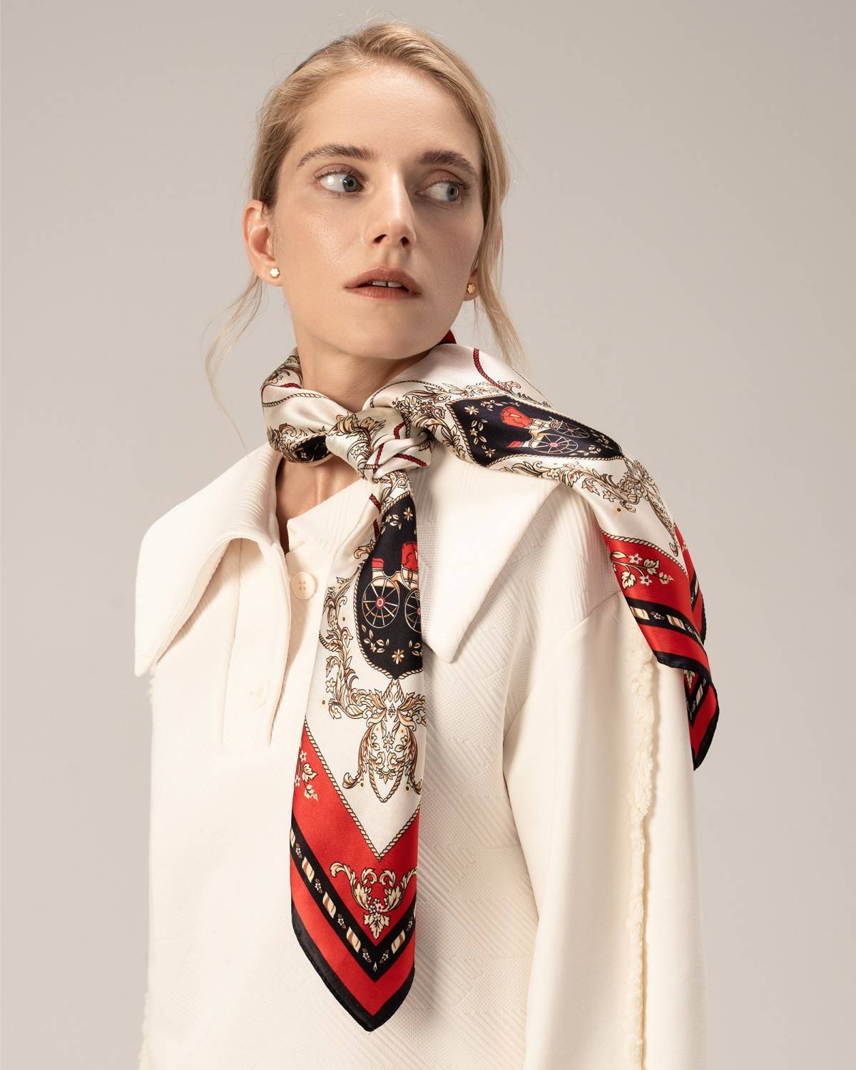 A woman models a white top paired with a luxurious silk red scarf, exuding elegance and fashion.