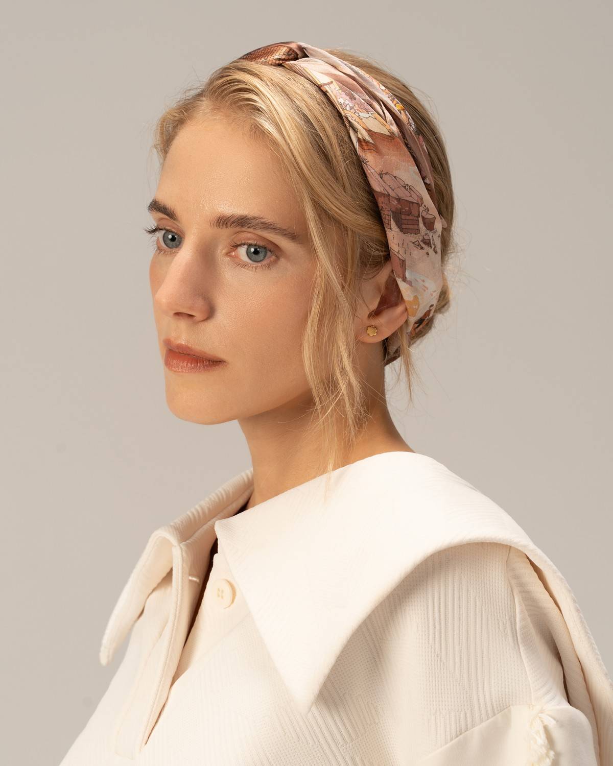 A model wearing a white shirt and a silk head scarf, embodying the grace of Chinese painting in her pose.